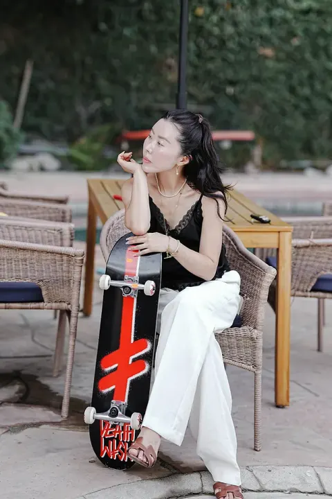 金老佛爺滑板坐姿生活照，黑色背心搭配珍珠耳環與項鍊
